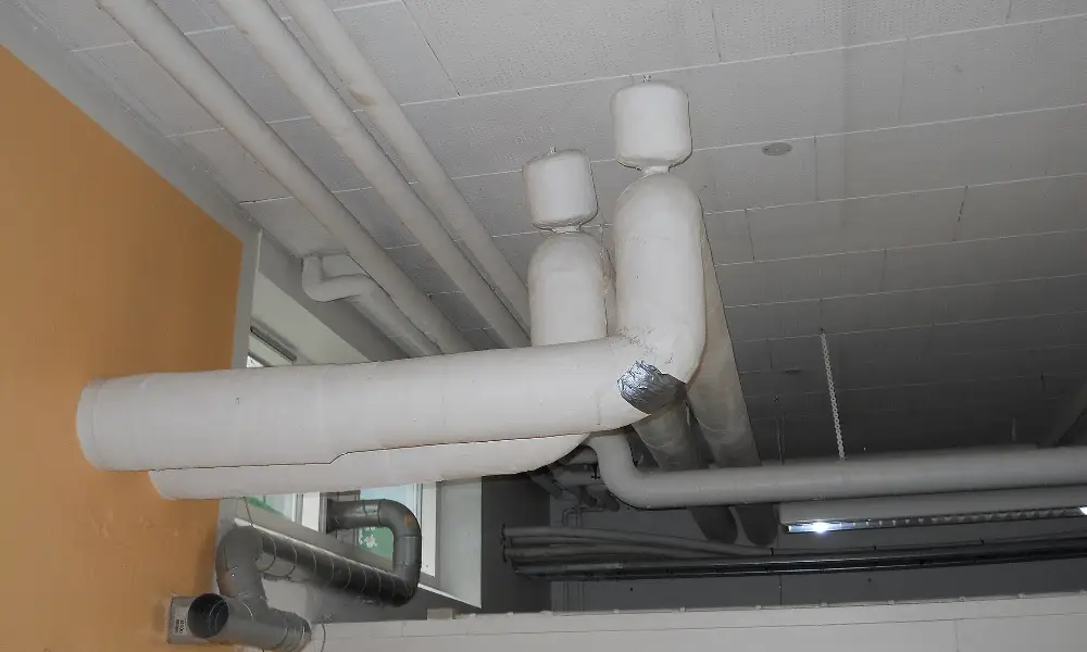 White asbestos insulation wrapped around overhead pipes in a building
